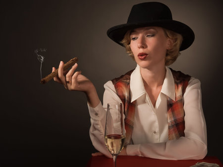 Portrait of beautiful woman in a black hat with a cigar