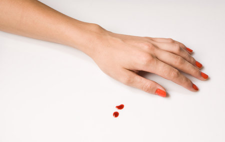 woman's hand and a drop of blood over whiteの写真素材