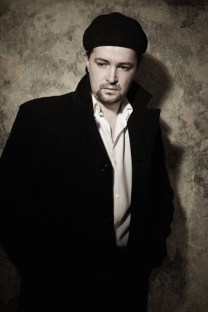 Portrait of a man in black on a sharpened wall background