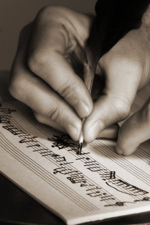 The hand writes musical notes a feather