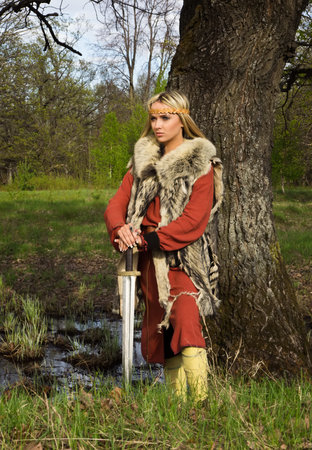 Portrait of the blonde girl in the Scandinavian suit with swordの写真素材