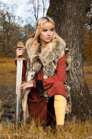 Portrait of the blonde girl in the Scandinavian suit with swordの写真素材