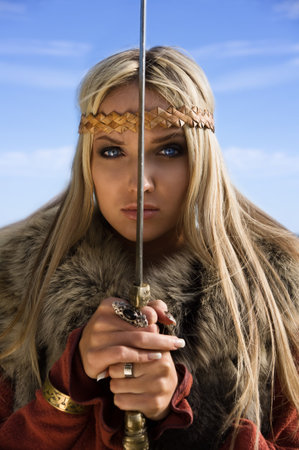 Portrait of the blonde girl in the Scandinavian suit with swordの写真素材