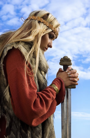 Portrait of the blonde girl in the Scandinavian suit with swordの写真素材
