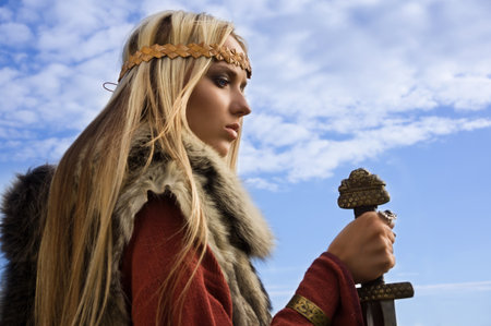 Portrait of the blonde girl in the Scandinavian suit with swordの写真素材