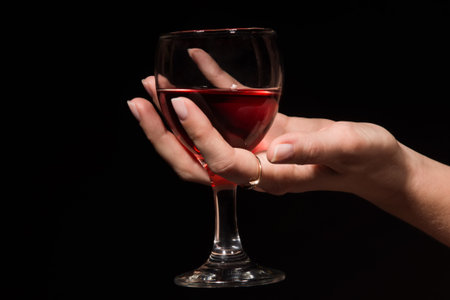 The image of a glass with a red wine in a female handの写真素材