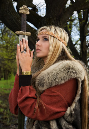 Viking girl warrior with sword in a woodの写真素材