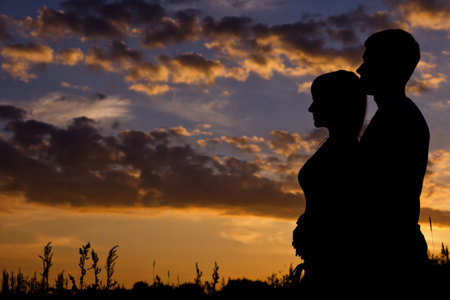 Silhouette of a young couple with the sunset behind themの写真素材