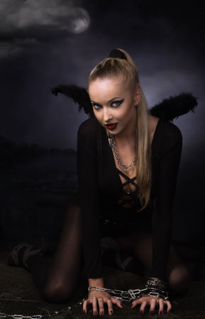 Beauty devil girl in a chains over dark sea backgroundの写真素材