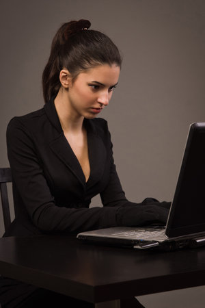 Spy girl in a black suit with laptopの写真素材