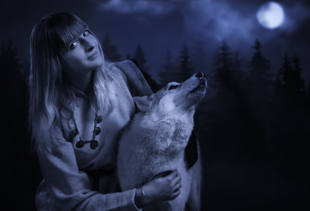 Slavonian girl in the traditional suit and gey wolf in the deep forestの写真素材