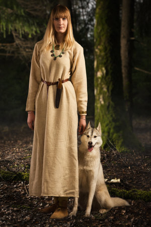 Slavonian girl in the traditional suit and siberian husky in the deep forestの写真素材