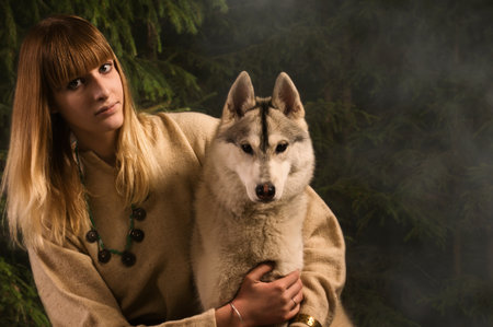 Slavonian girl in the traditional suit and siberian husky in the deep forest