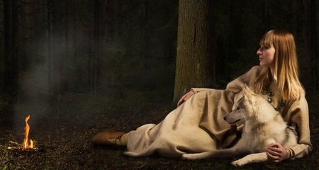 Slavonian girl in the traditional suit and siberian husky in the deep forest
