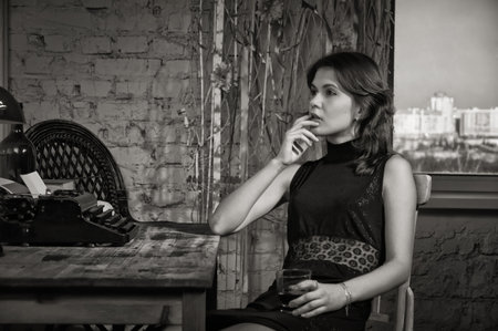 Elegant woman in black at the table with the old typewriterの写真素材