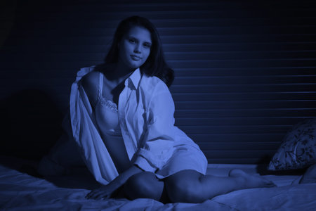 Pretty blonde girl sitting on the bedの写真素材