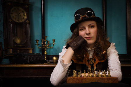 Steam punk girl in a vintage room plays chessの写真素材