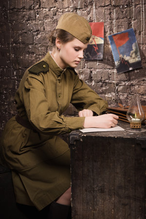 Soviet female soldier in uniform of WW II writes a letterの写真素材