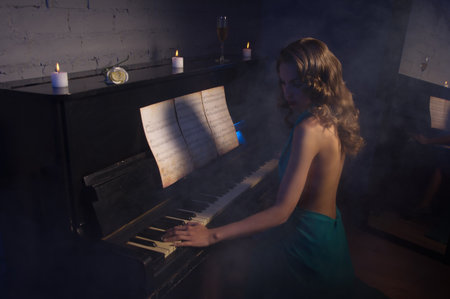 Pretty woman in evening dress playing pianoの写真素材