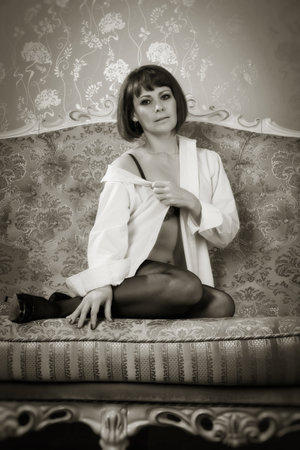 Attractive woman in sexy lingerie posing on a luxurious couchの写真素材