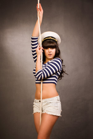 Beautiful navy pinup girl wearing striped sailor top and admirals hat with ropeの写真素材