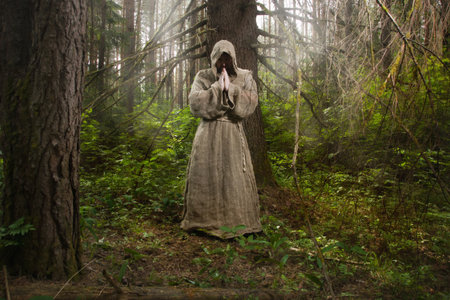 Medieval monk praying in the misty forestの写真素材