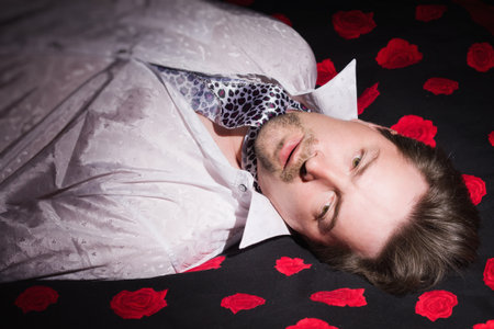 Corpse of business man lays on a bedの写真素材