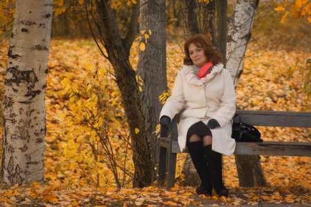 Beautiful elegant middle-aged woman in the autumn parkの写真素材