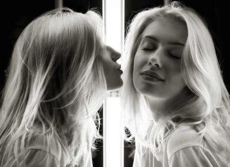 Mirrored shot of a gorgeous young blond kissing herselfの写真素材