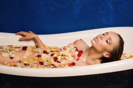 Beautiful sexy woman in bath with flowers petals. Spa body care.の写真素材