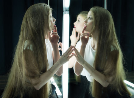 beautiful sexy girl and her reflection in mirror tableの写真素材
