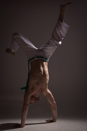 Capoeira, Man standing on one hand, white pants.の写真素材