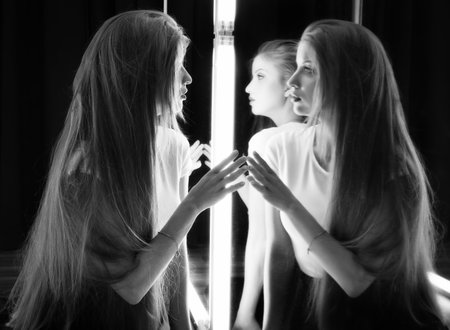 beautiful sexy girl and her reflection in mirror tableの写真素材