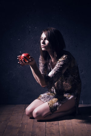 Asylum. Lonely mad woman with red apple sitting on a floor. Low key.の写真素材