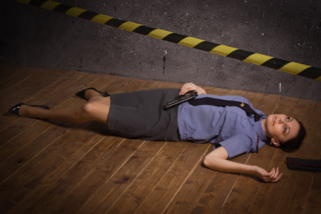 Crime scene imitation. Woman police officer lying on a floorの写真素材