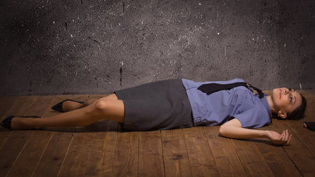 Crime scene imitation. Woman police officer lying on a floorの写真素材