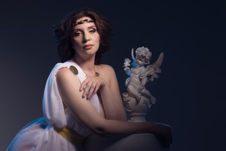 Beautiful Woman Wearing White Greek Toga in a dark antique interiorの写真素材