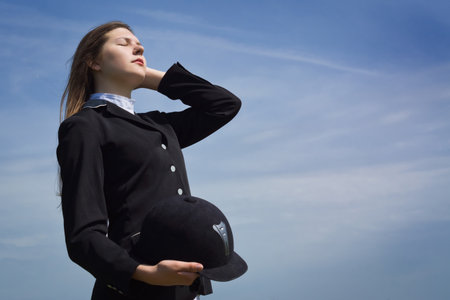 Beautiful girl jockey dressing uniform posing outdoorsの写真素材