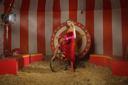 Circus actress in a red dress on retro bikeの写真素材