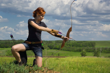 Archery woman bends bow archer target narrow in the summer fieldの写真素材