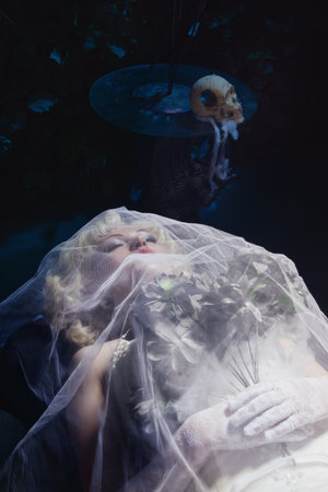 Sleeping Beauty. Beautiful lifeless bride in white dress lying on the shore in a tomb. Dark mystery sceneの写真素材