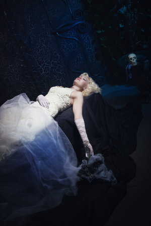 Sleeping Beauty. Beautiful lifeless bride in white dress lying on the shore in a tomb. Dark mystery...