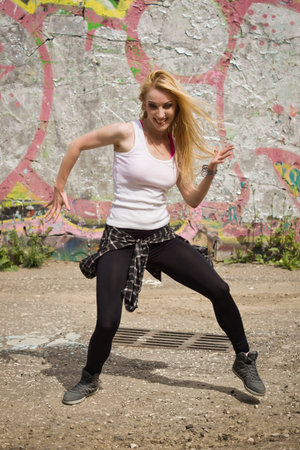 Young girl dancing on graffiti background. Dancing and urban culture concept.の写真素材