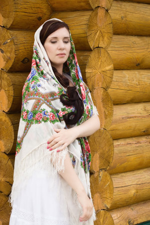 Russian woman in traditional clothes on background of the hutの写真素材