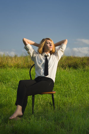 Beauty woman sitting in the armchair at the field and looking in expanseの写真素材
