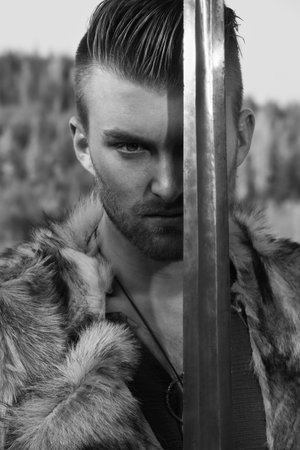 Male dressed in Barbarian style with sword in the mountainsの写真素材