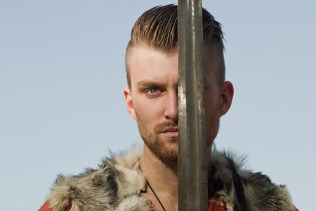 Male dressed in Barbarian style with sword in the mountains