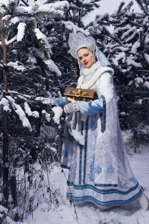 Russian Christmas characters: Snegurochka (Snow Maiden) with gifts bag in the winter forestの写真素材