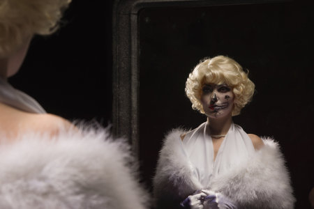 Beautiful woman with make-up skeleton looks at himself in the mirror