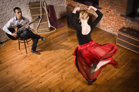 Young woman dancing flamenco in traditional flamenco dress and a man playing the guitarの写真素材